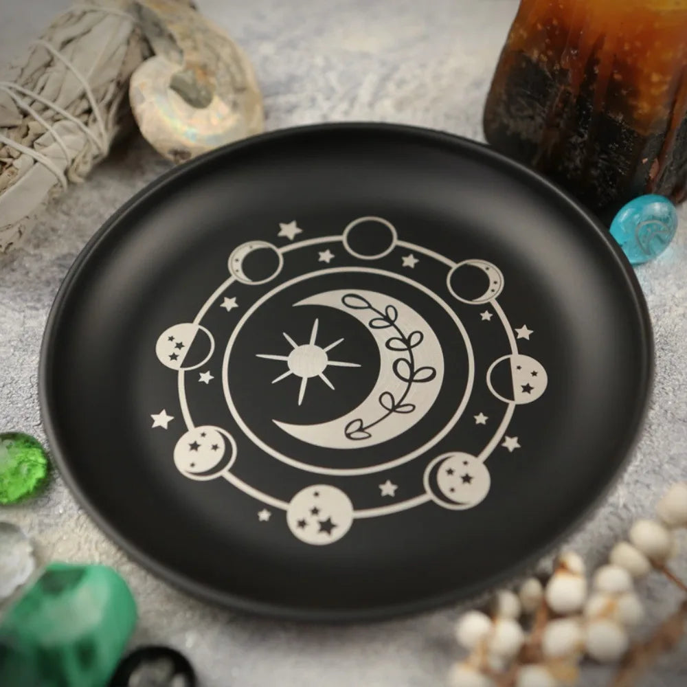 Un plat décoratif noir avec un motif circulaire blanc de corps célestes et une lune en croissant.