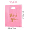 A pink plastic gift bag with gold script writing that says Thank you