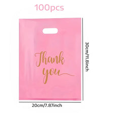 A pink plastic gift bag with gold script writing that says Thank you