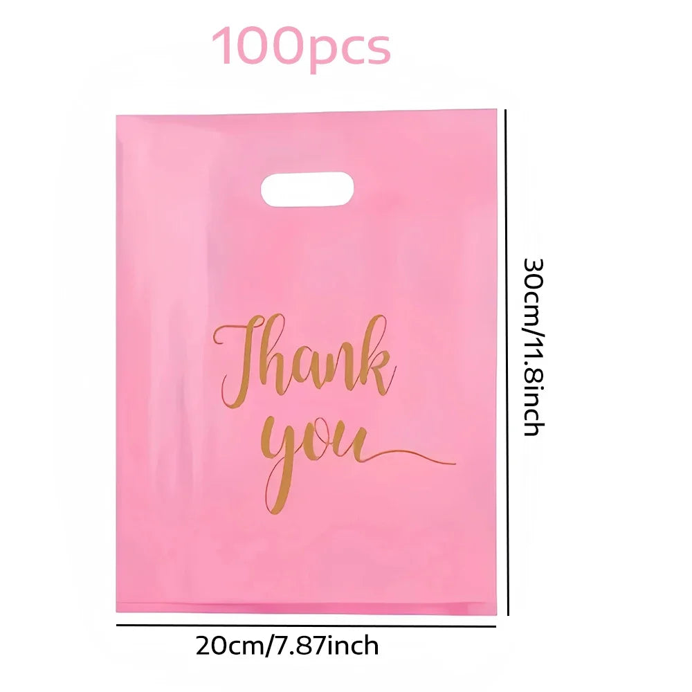 A pink plastic gift bag with gold script writing that says Thank you
