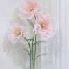 A large artificial silk pink poppy flower displayed on a green stand against a white background.