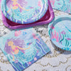 A set of mermaid-themed party tableware including plates, cups, and napkins in shades of purple, blue, and teal.
