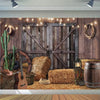 A rustic backdrop featuring a weathered wooden barn door, hay bales, and leather goods for western photography.