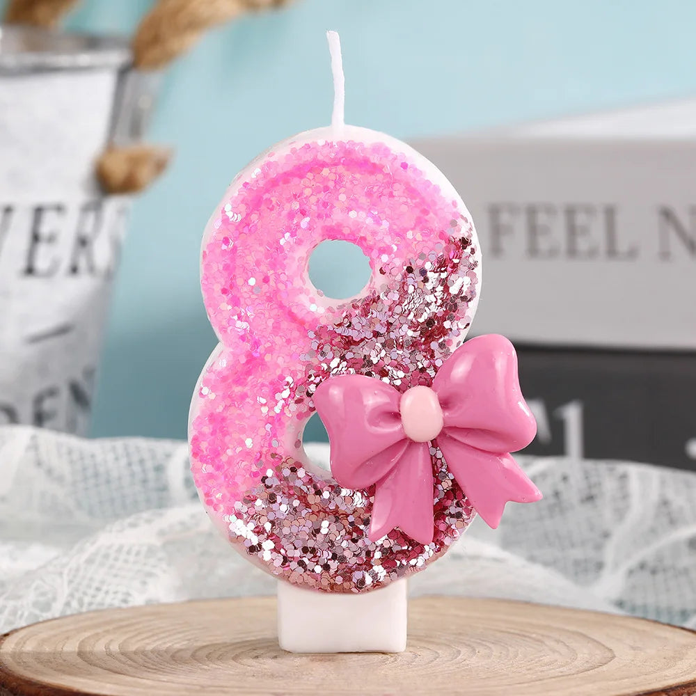 Pink glitter number 8 candle with a pink bow on a white stand for birthday celebrations