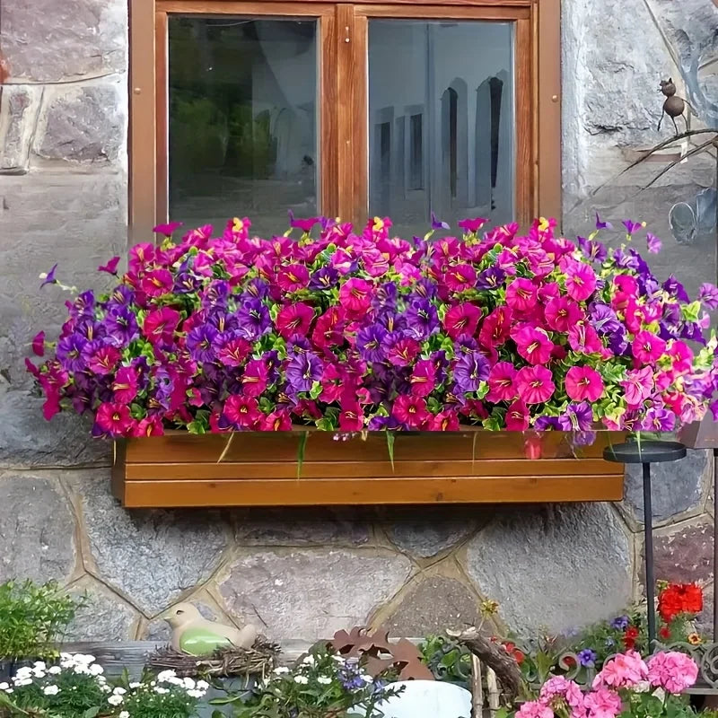A vibrant display of artificial outdoor decorative flowers in various shades of pink and purple arranged in a wooden planter.