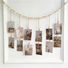 A garland of small framed photos hangs from a string against a white frame.