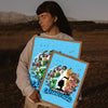 A person holds a framed print featuring Minecraft characters and scenery against a blue background.
