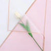 A pale yellow tulip is visible within a pink paper fold with gold edge wrapping.