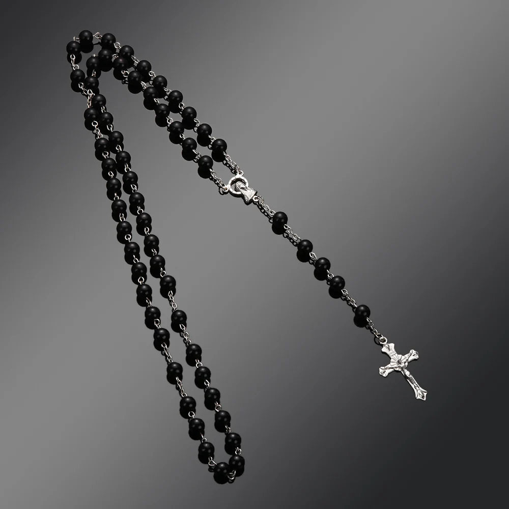A black beaded rosary necklace featuring a vintage cross and Virgin Mary pendant.