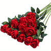 Un ramo de rosas artificiales de seda rojo intenso con hojas verdes.