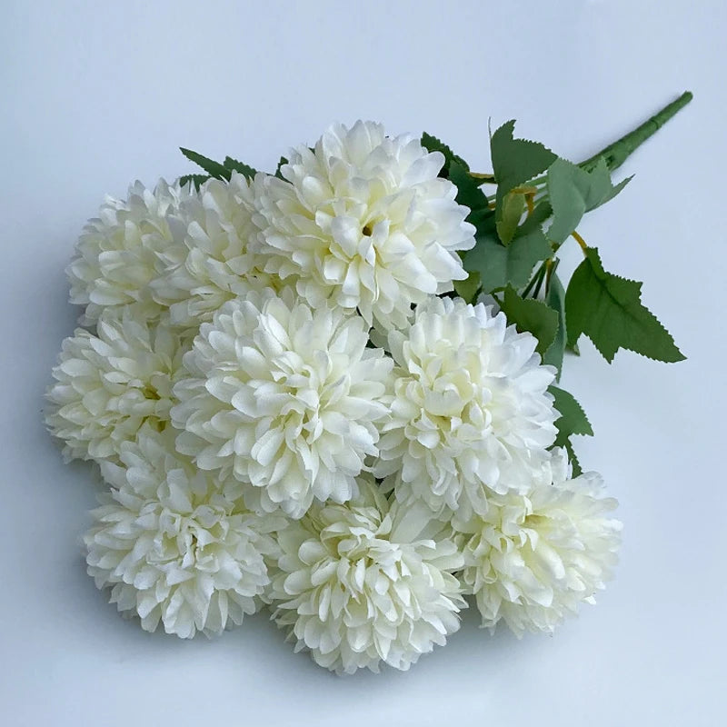 A bouquet of artificial white hydrangea and camellia flowers with green leaves.