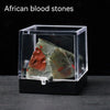 A clear box displays a rough specimen of African blood stones, featuring reddish and greenish crystals.