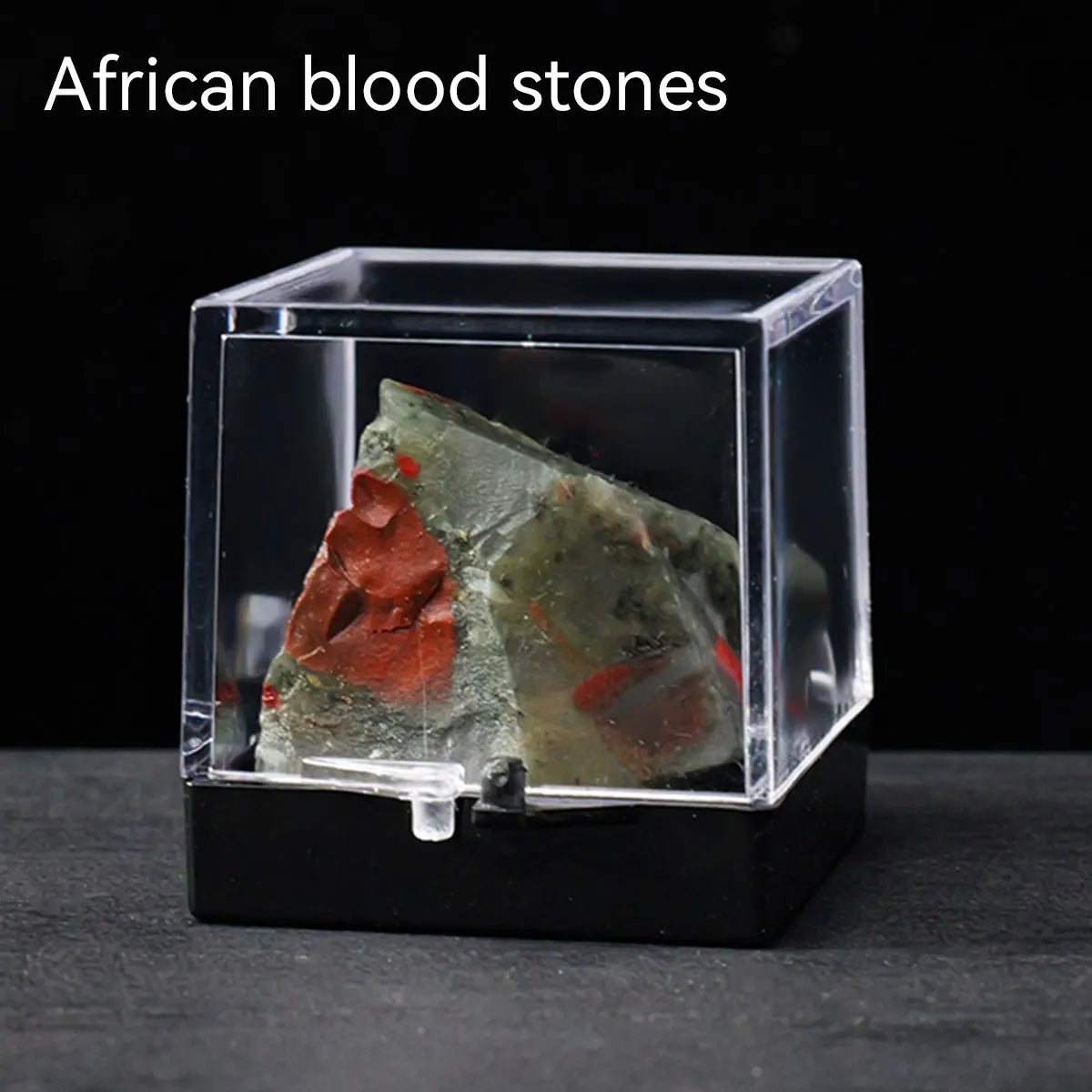 A clear box displays a rough specimen of African blood stones, featuring reddish and greenish crystals.