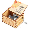 A vintage hand-cranked wooden music box with a lid featuring a sun design and a silver crank mechanism.