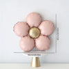 A set of five matte pink foil balloons shaped like daisies with a gold center, displayed on a white pedestal.