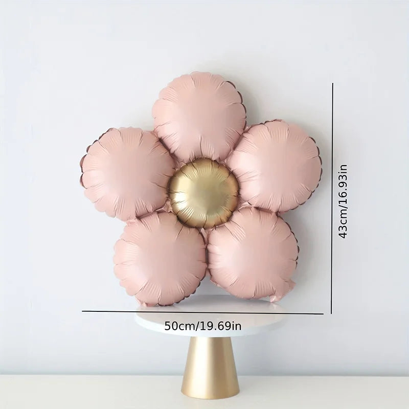 A set of five matte pink foil balloons shaped like daisies with a gold center, displayed on a white pedestal.
