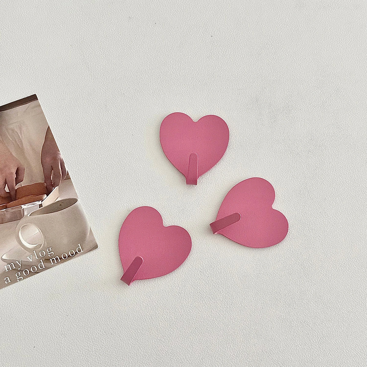 A set of three pink heart-shaped adhesive key hooks for use in various rooms.
