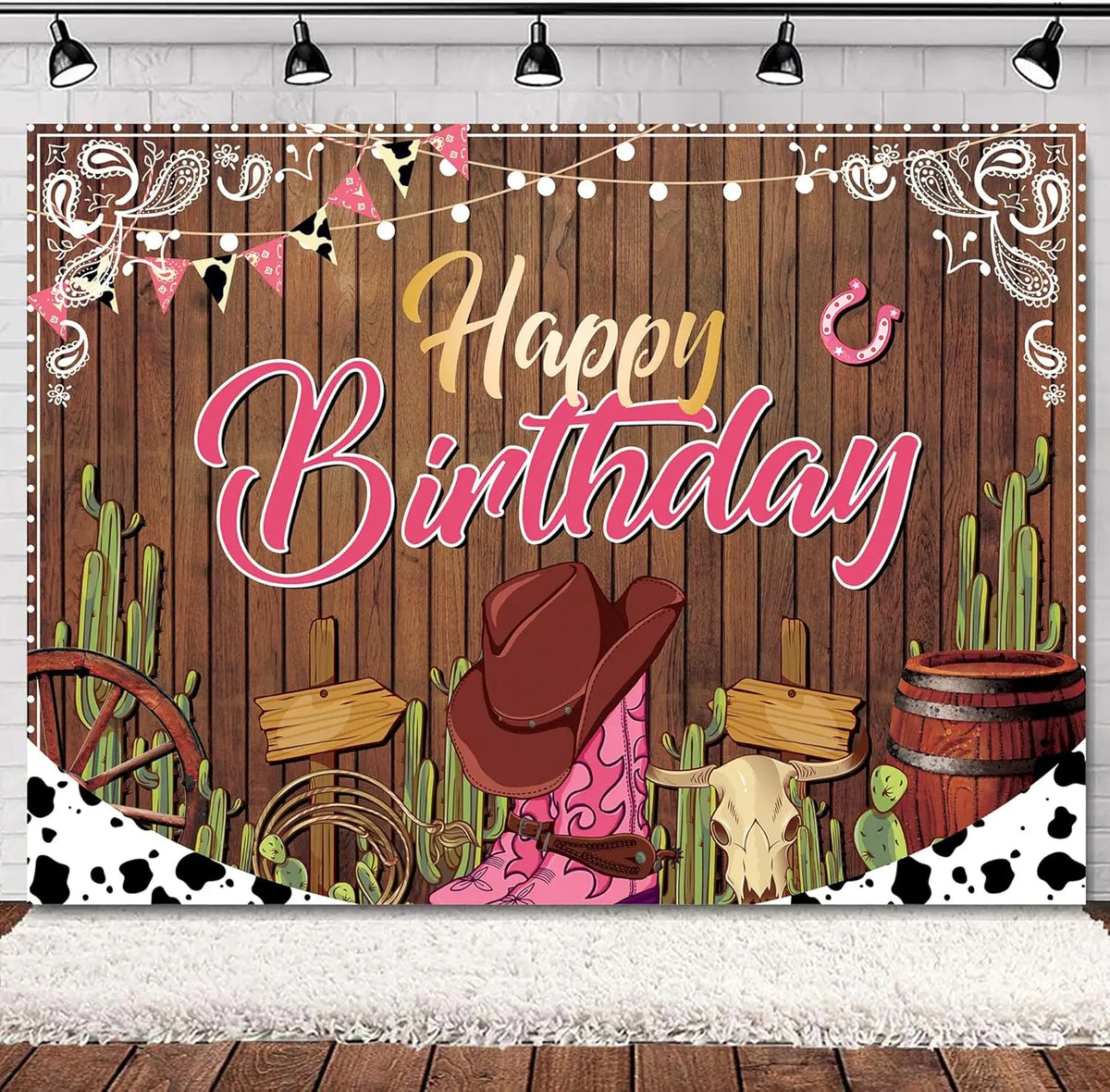 A rustic western backdrop featuring a wooden barn door, cacti, and pink floral elements for a birthday theme.