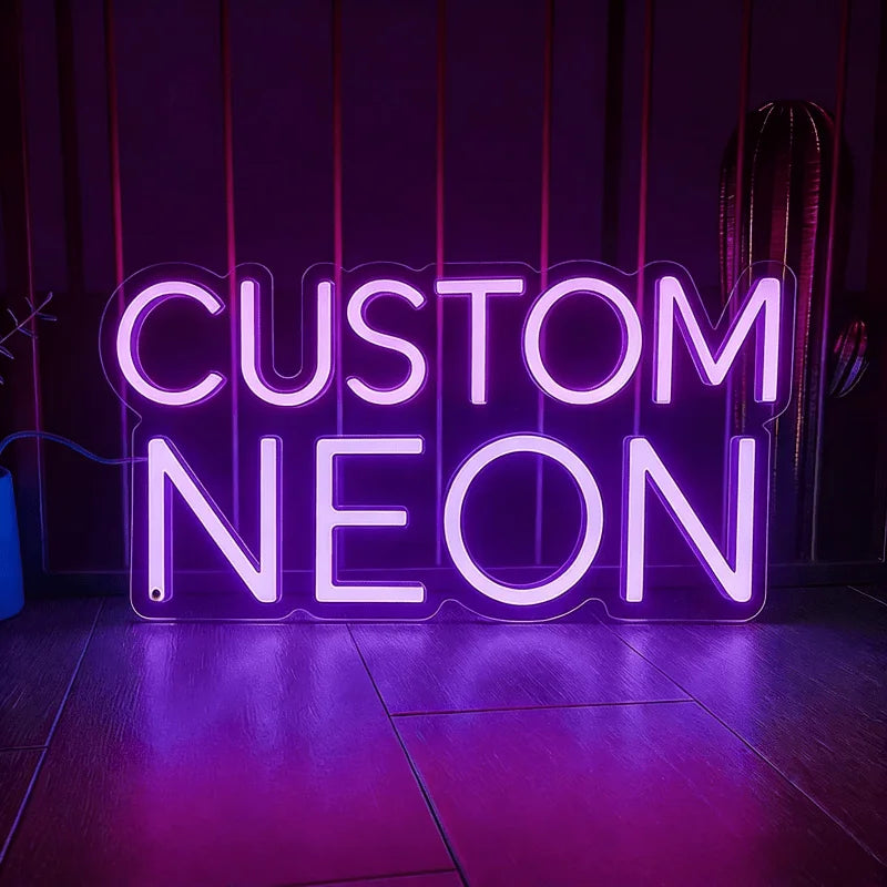 A glowing purple neon sign spelling out CUSTOM NEON on a dark wooden floor.