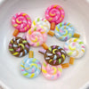 A collection of twenty colorful resin candy charms in various swirl patterns and colors arranged on a white plate.