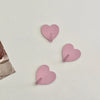 Three pink heart-shaped adhesive hooks are displayed on a white surface.