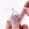 A hand holds a transparent self-adhesive wall hook for pictures and frames.