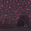 A dark room decorated with pink glow-in-the-dark stars on the wall, featuring a tent structure and furniture.