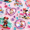 A collection of colorful self-adhesive rhinestone embellishments and Disney-themed stickers on a pink background.