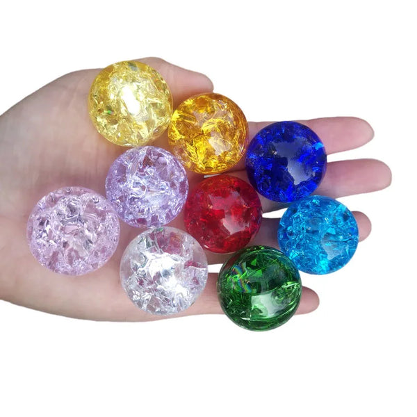 A hand holds several colorful, translucent crystal ice crack balls in various shades of yellow, purple, blue, and green.