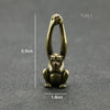 Vintage brass monkey key chain charm with a loop, shown against a dark gray background.