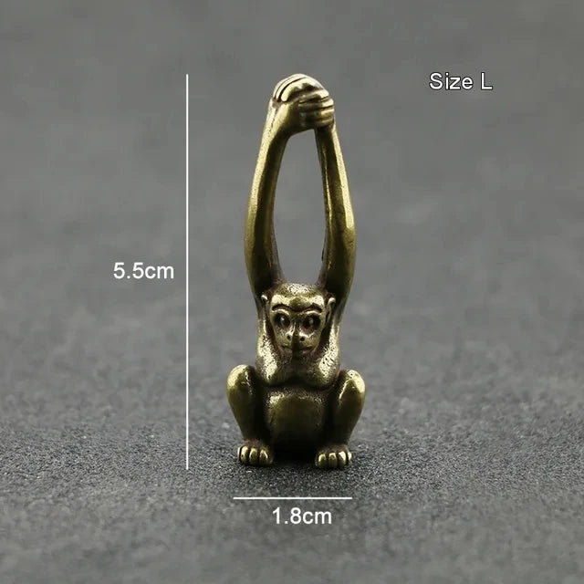 Vintage brass monkey key chain charm with a loop, shown against a dark gray background.