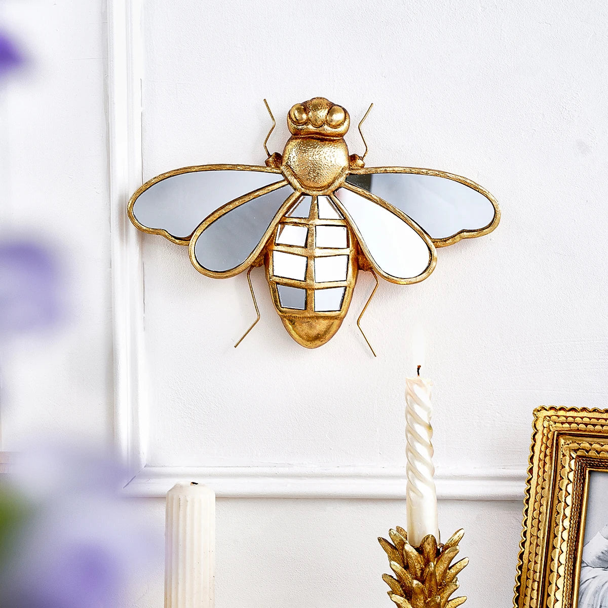 Gold resin animal wall hanging decor featuring a dragonfly design mounted on a white wall.
