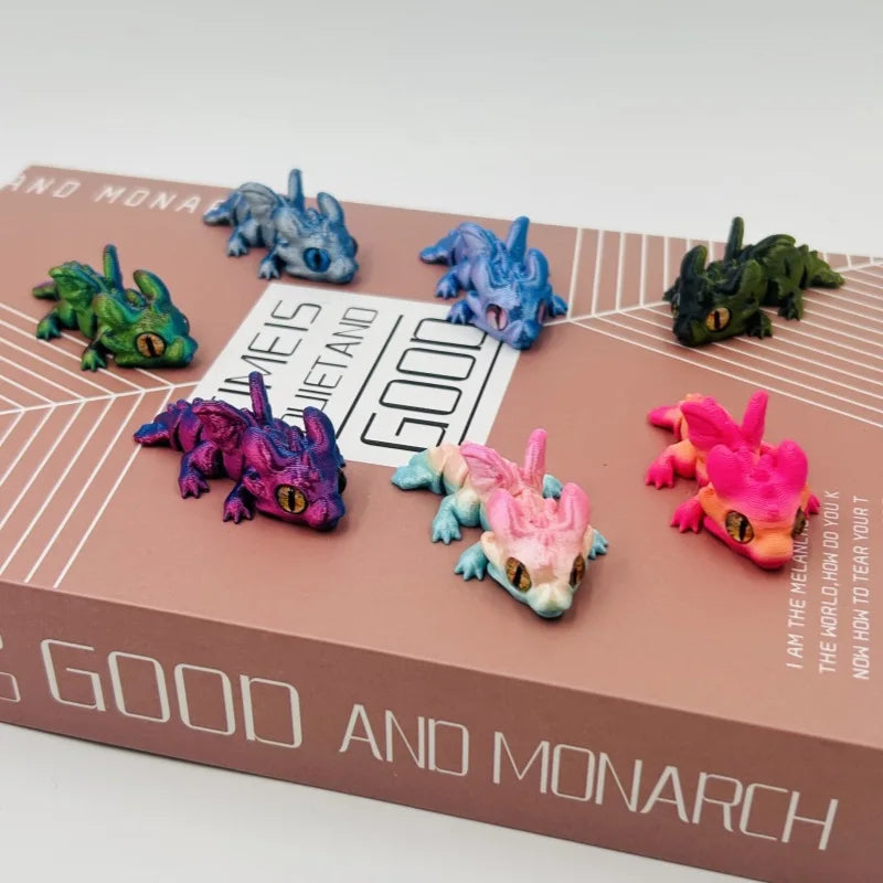 A collection of articulated baby dragon figurines in various shades of blue, green, and pink displayed on a brown box.