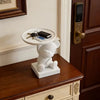 A white bear figurine holds a tray with keys and a smartphone on a wooden cabinet top.