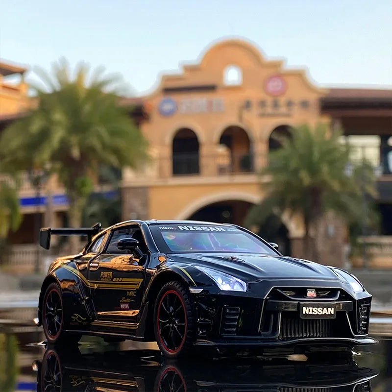 A black Nissan GT-R diecast model is displayed on a reflective surface with a blurred outdoor background.