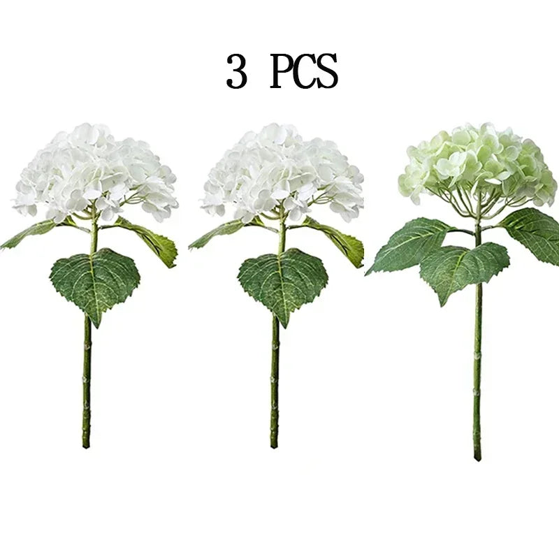 Three stems of white artificial hydrangea flowers on green leaves
