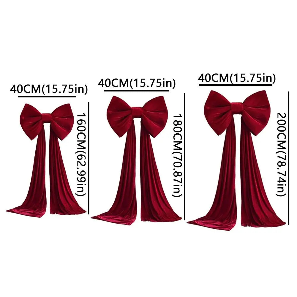 Three velvet red Christmas tree topper bows of varying sizes with long streamers.