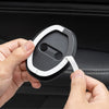 A hand is holding a black silicone car door lock protector with a white bumper pad, demonstrating its design.