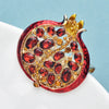 A detailed crystal pomegranate brooch pin featuring deep red stones and gold accents.