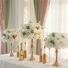 A gold-toned centerpiece featuring white flowers and greenery on a draped table.