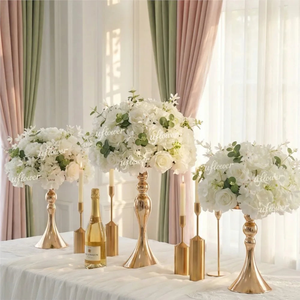 A gold-toned centerpiece featuring white flowers and greenery on a draped table.