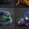 A set of three 3D printed rotatable snake art models in black, yellow, and blue colors.