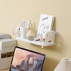 White adhesive elephant storage rack with a sign and various pens mounted on a light-colored wall.