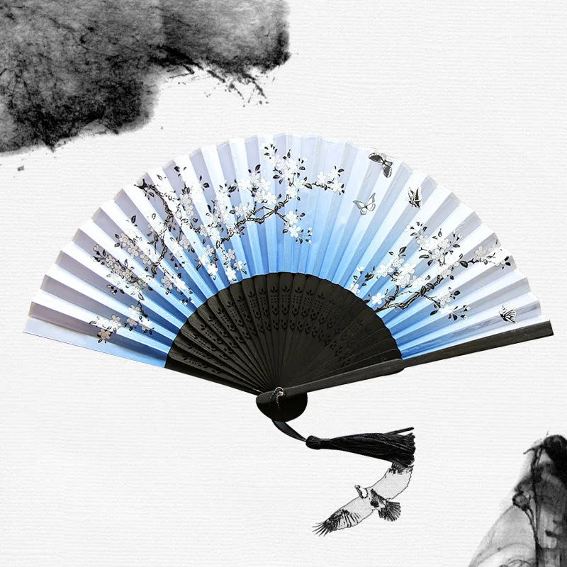 A vintage bamboo folding hand fan with light blue and white floral patterns is shown against a white background.