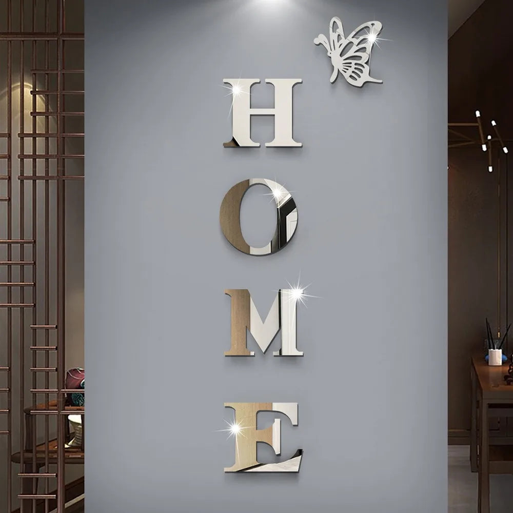 Silver acrylic wall stickers spelling out HOME with a butterfly design on a gray wall.