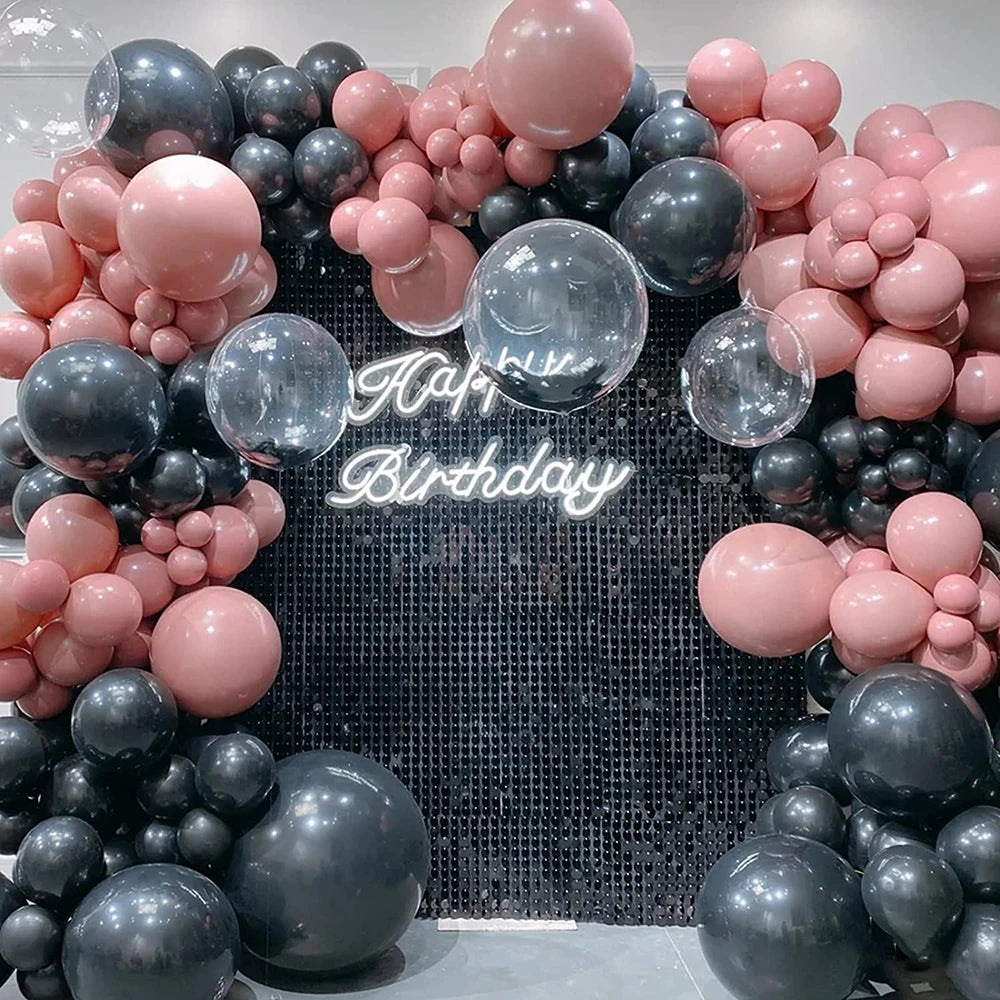 A dense arrangement of pink and gray latex balloons forming a backdrop for a birthday celebration.