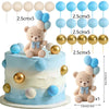 A tiered cake decorated with blue and gold balloons and a teddy bear topper set.