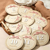 A collection of wooden baby milestone cards showing numbers 1 through 12 for newborn keepsakes