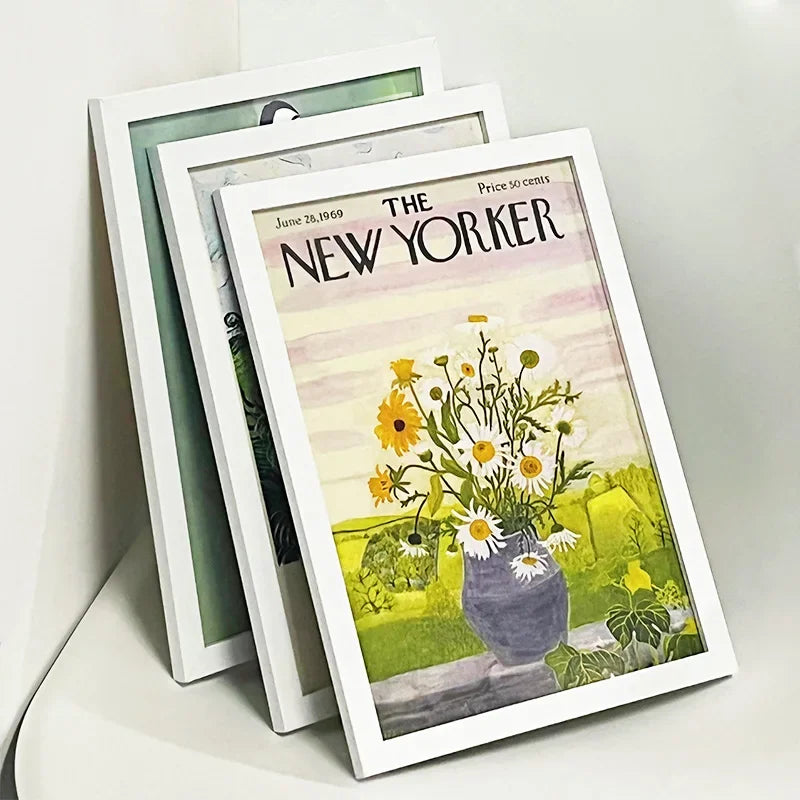 A set of three white picture frames displaying a vintage New Yorker magazine cover.
