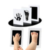 A set of white inkless baby handprint and footprint keepsakes displayed on a black surface.